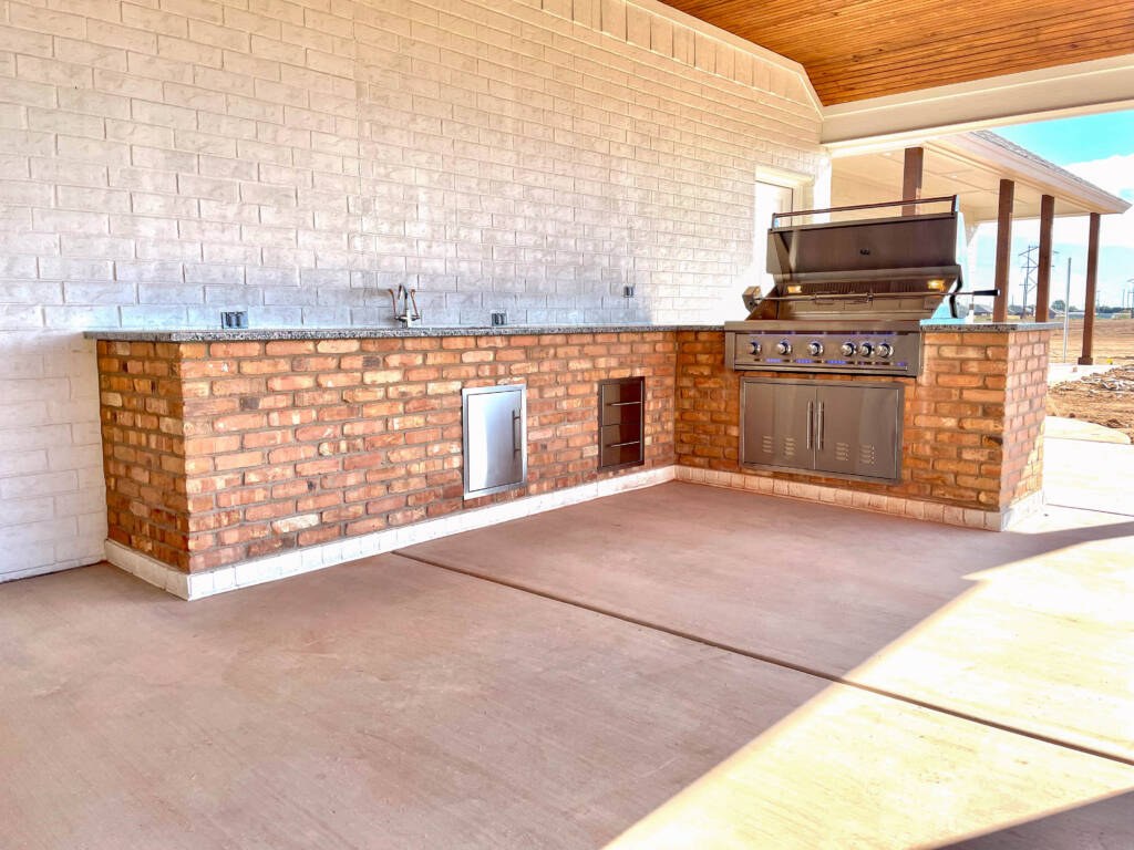 Outdoor kitchen with stone counters and built-in grill in Lubbock, TX backyard