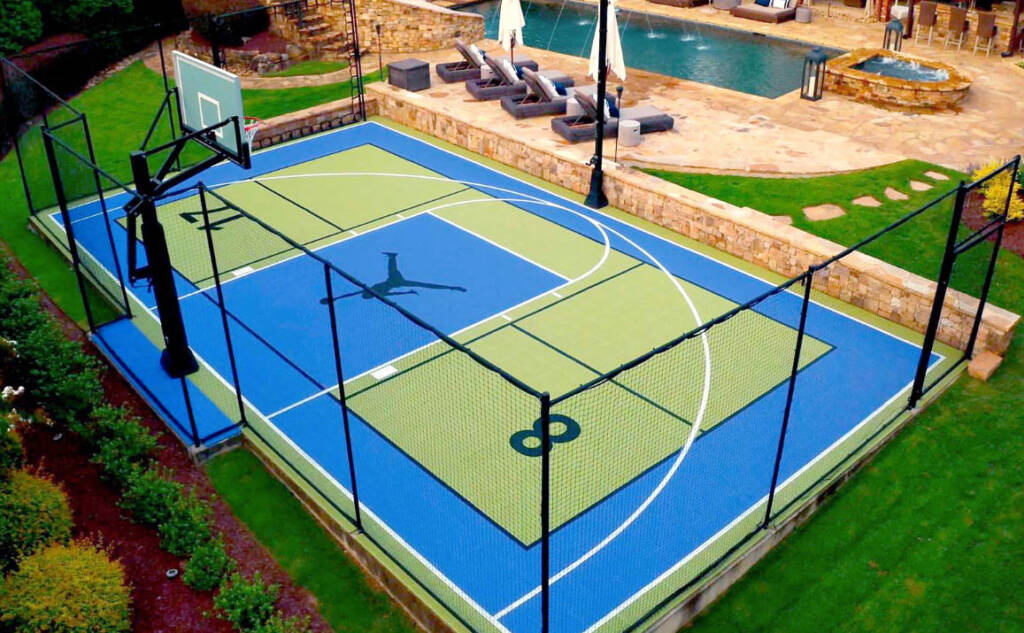 Custom basketball half-court with logo and fencing in West Texas backyard